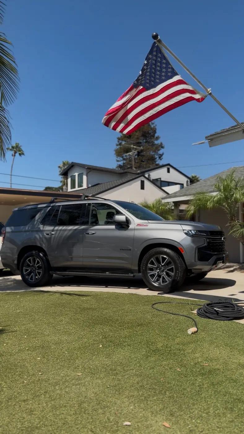 Grey Chevy Tahoe on the lawn under an American flag